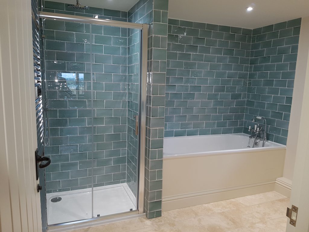 Bathroom with green metro wall tiles, a glass shower enclosure and a built-in bath