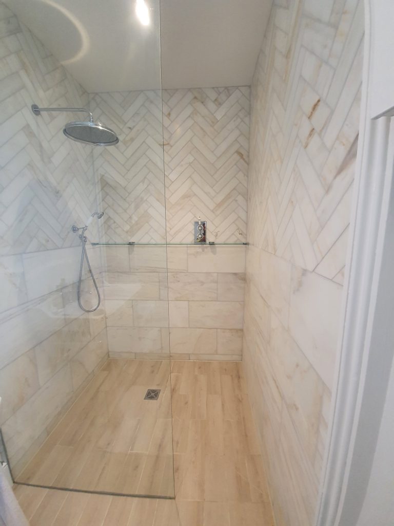 Walk-in shower with marble-effect wall tiles, a herringbone feature panel and a wall niche