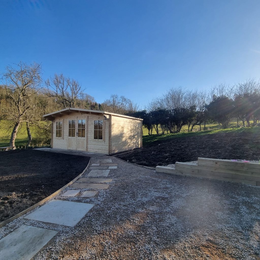 Timber garden room with a stone path, set in a landscaped garden
