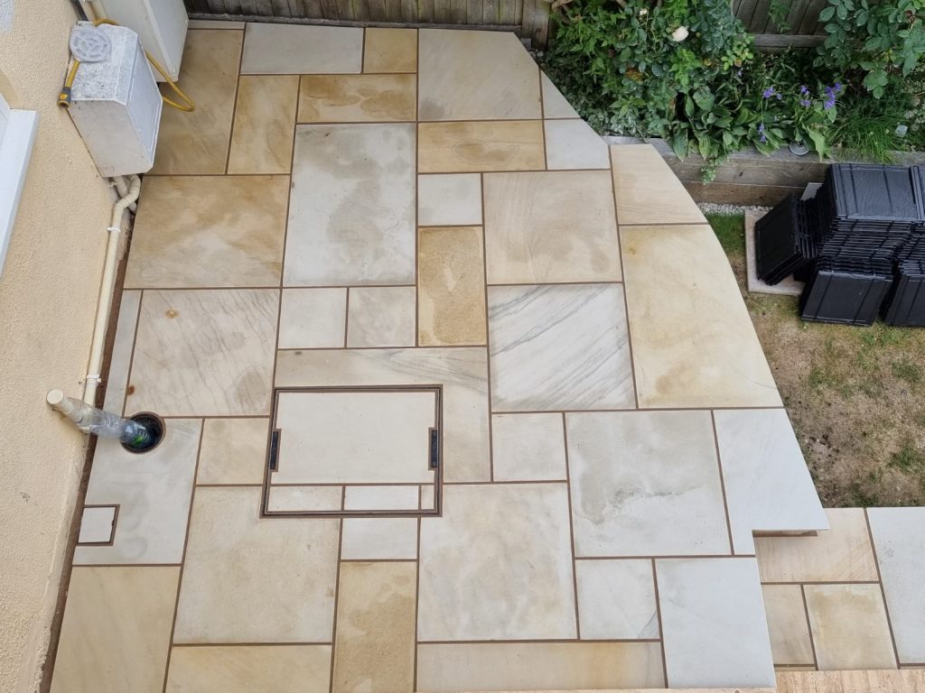 Sandstone patio laid in a random pattern with a recessed access cover