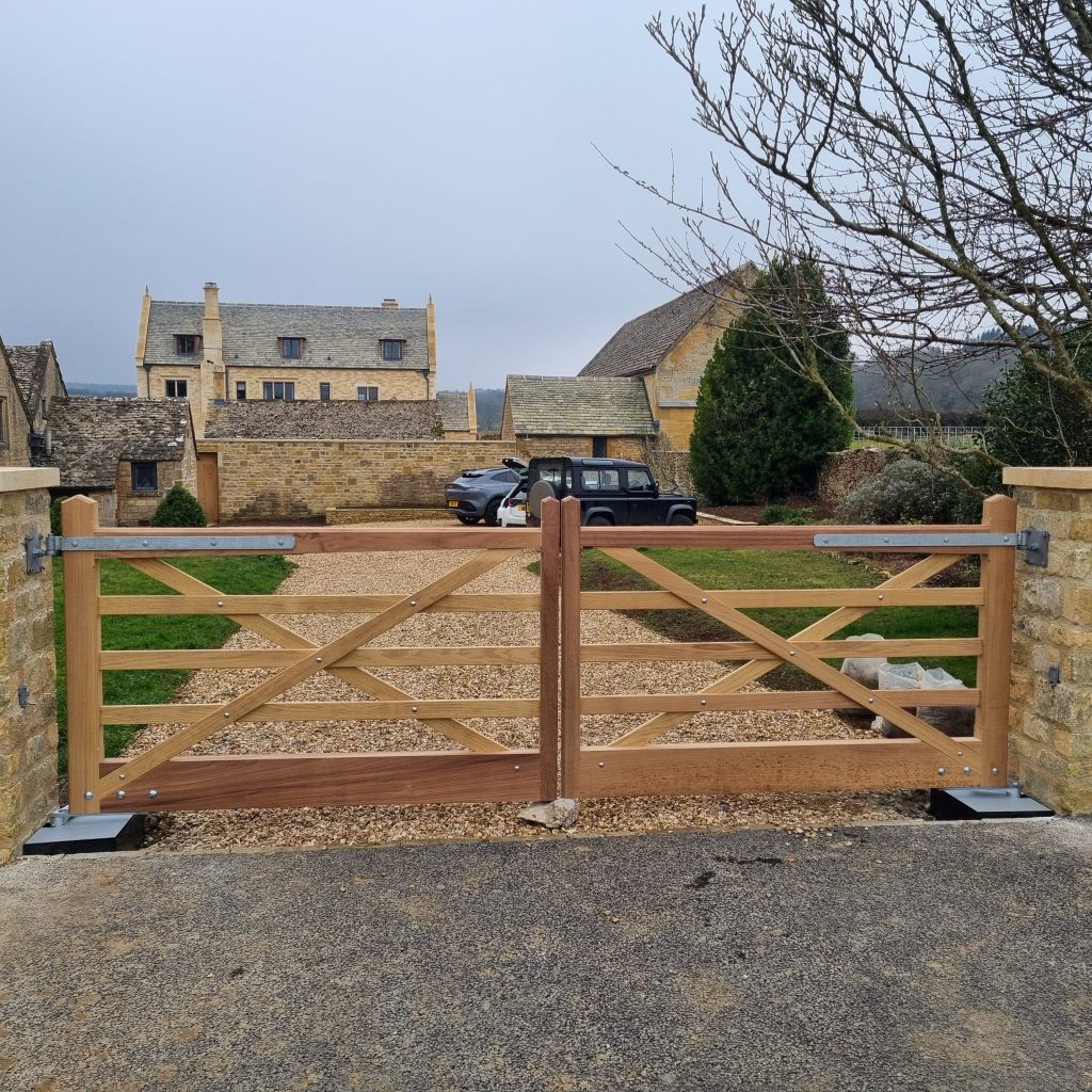 Bespoke oak double gates hung between Cotswold stone pillars