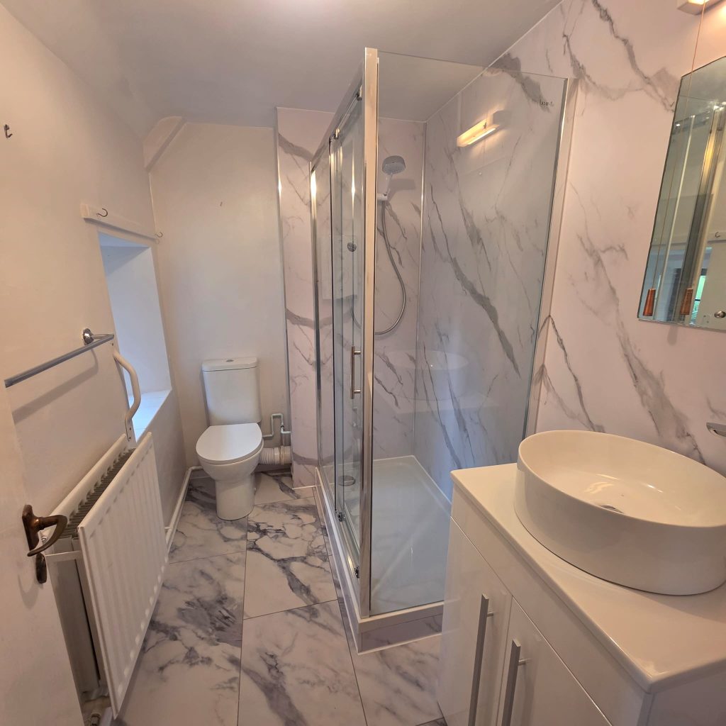 Bathroom renovation with marble-effect tiles, a glass shower enclosure and a vessel basin