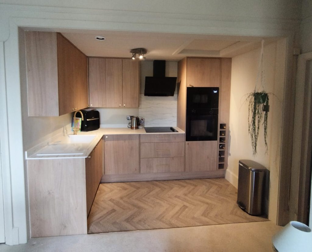 Kitchen renovation with light oak-effect units, white worktops and a herringbone floor