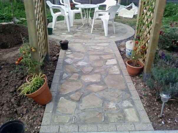 Crazy-paving stone path leading to a circular patio with garden seating