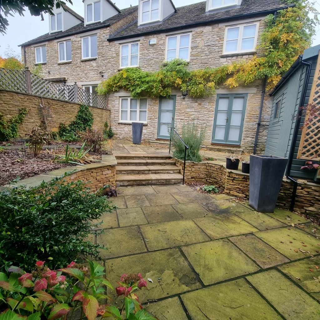 Terraced garden with curved dry stone walls, stone steps and a sandstone patio